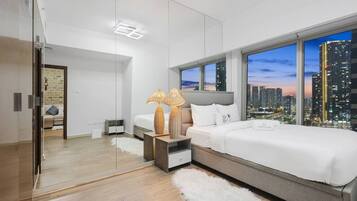Une chambre moderne avec vue sur la ville, un grand lit, des tables de chevet et un miroir.