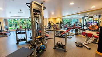 A gym with various exercise equipment, a bench, and a mirrored wall.