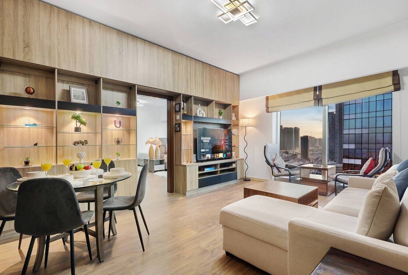 A modern living room with a sofa, dining table, chairs, and a TV.