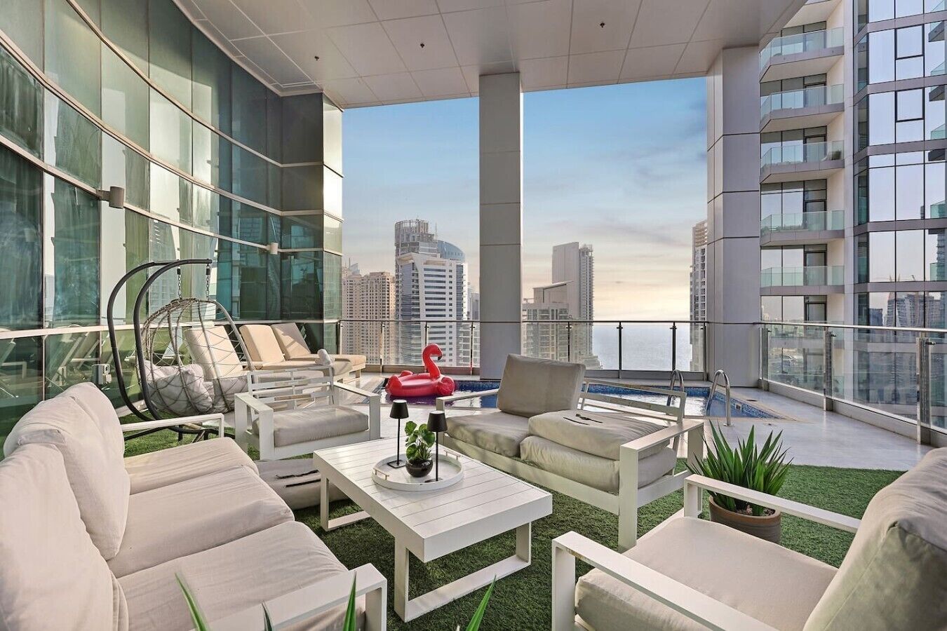 A modern rooftop lounge with seating, a pool, and a city view.