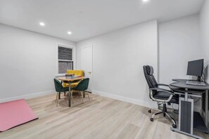 A room with a desk, two chairs, a small table with books, a pink mat, and a window with a brick wall view. - Downtown luxury house close to the nature (Ottawa)