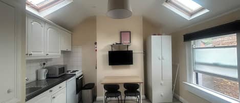 Una cocina funcional con comedor, dos sillas negras, una mesa y un refrigerador blanco.