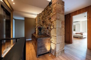 Un interior moderno con una pared de piedra, un banco de madera y vista a otra habitación.