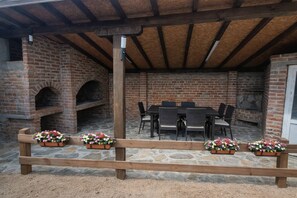 A brick patio with a stone table and chairs, a wooden fence, and flower planters. - Plitvice Green apartment with Sauna for families 1-8 people (Smoljanac)