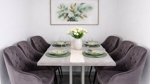 A dining area with a marble floor, grey upholstered chairs, a white table, and a framed artwork above. - Plitvice Green apartment with Sauna for families 1-8 people (Smoljanac)