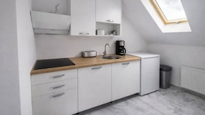 A modern kitchen with white cabinets, a wooden countertop, a sink, a toaster, a coffee maker, and a small refrigerator. - Plitvice Green apartment with Sauna for families 1-8 people (Smoljanac)