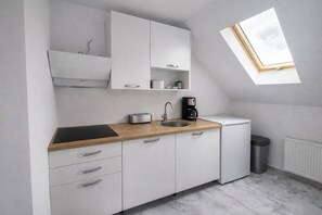 Eine moderne Küche mit weißen Schränken, einer Holz Arbeitsplatte, einer Spüle, einem Toaster, einer Kaffeemaschine und einem kleinen Kühlschrank.