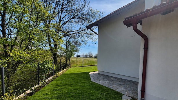 A residential property with a well-maintained lawn, a white building with a red roof, and a stone pathway leading to the entrance. - Plitvice Green apartment with Sauna for families 1-8 people (Smoljanac)