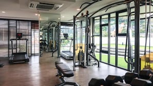 A gym with exercise equipment, a bench, and large windows. - 6th Avenue Surin by Win217 (Tambon Choeng Thale)