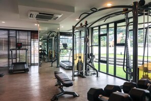 Un gimnasio con equipo de ejercicio, una banca y ventanas amplias.