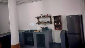 Eine Küche mit Gasherd, Kühlschrank, Holzregalen und einer Arbeitsplatte.