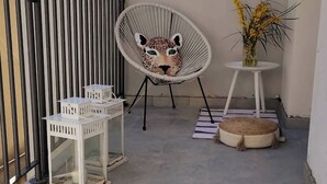 En stol med ett leopardmönstrat tyg, en vit lykta och ett litet bord med en vas med blommor.