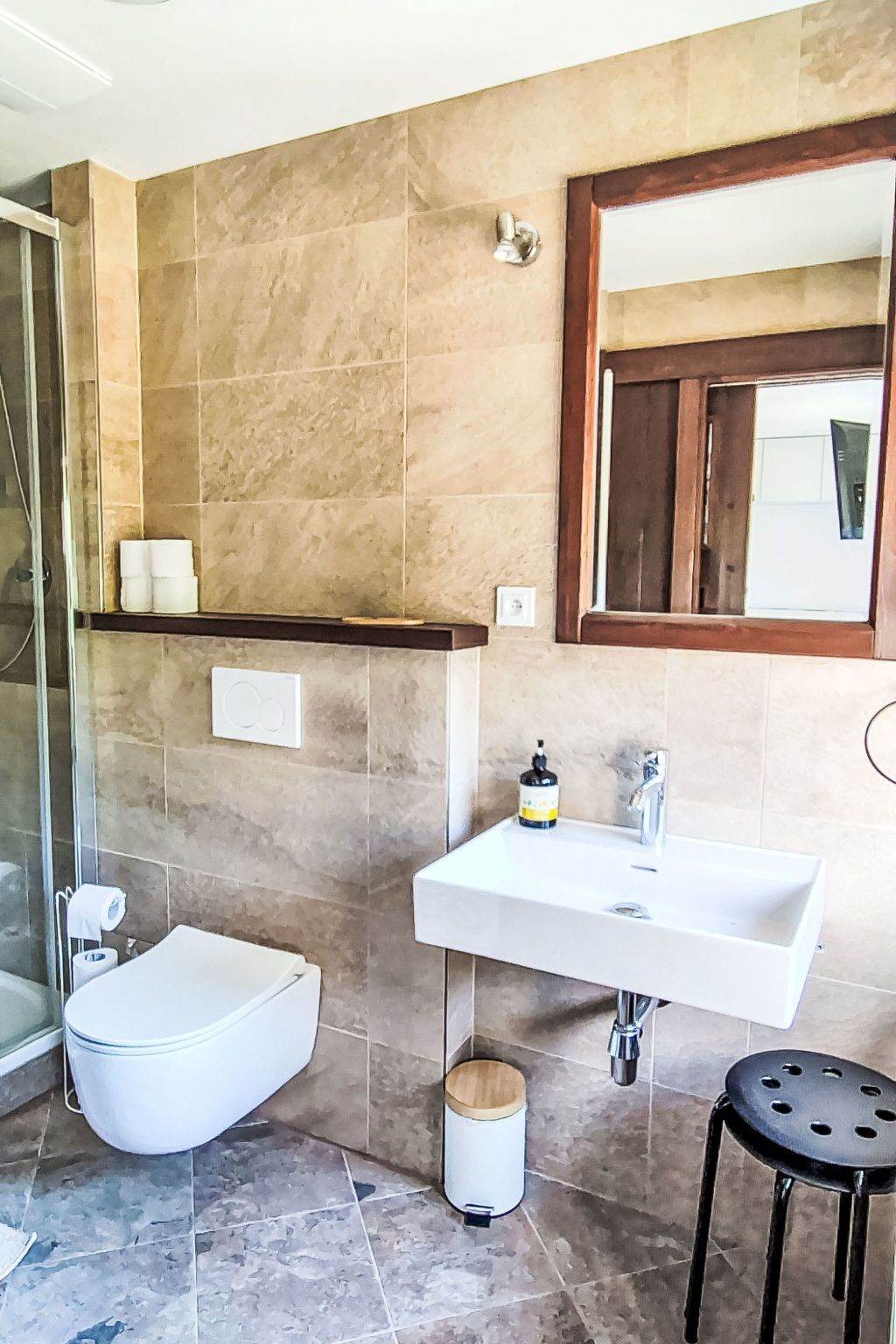 A bathroom with a bidet, a sink, a mirror, and a shower area.