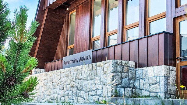 A building with a stone facade, wooden windows, and a sign reading 'Apartmány ARNIKA'. - Apartment Arnika by Interhome (Janov nad Nisou)