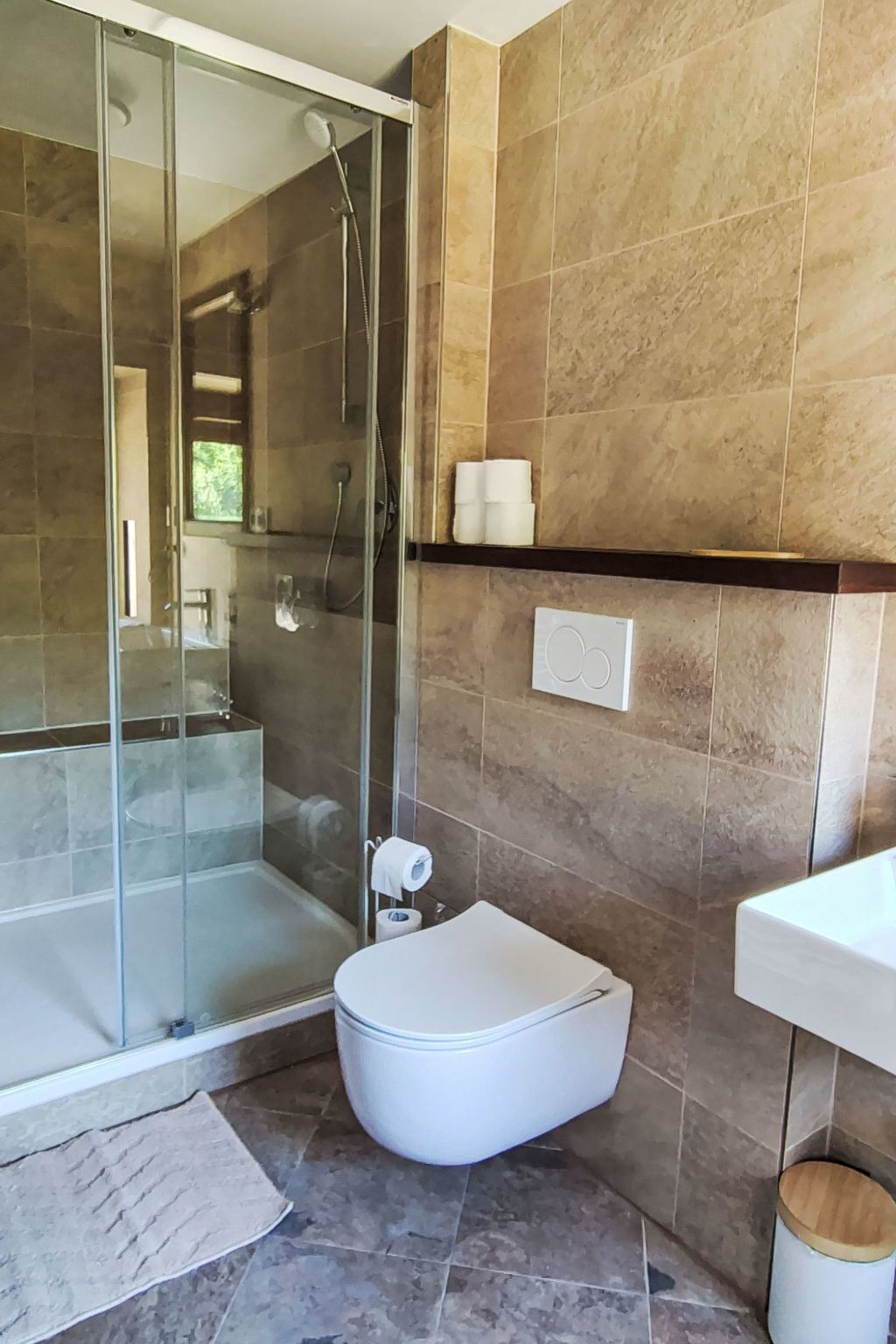 A modern bathroom with a glass-enclosed shower, a toilet, and a sink.
