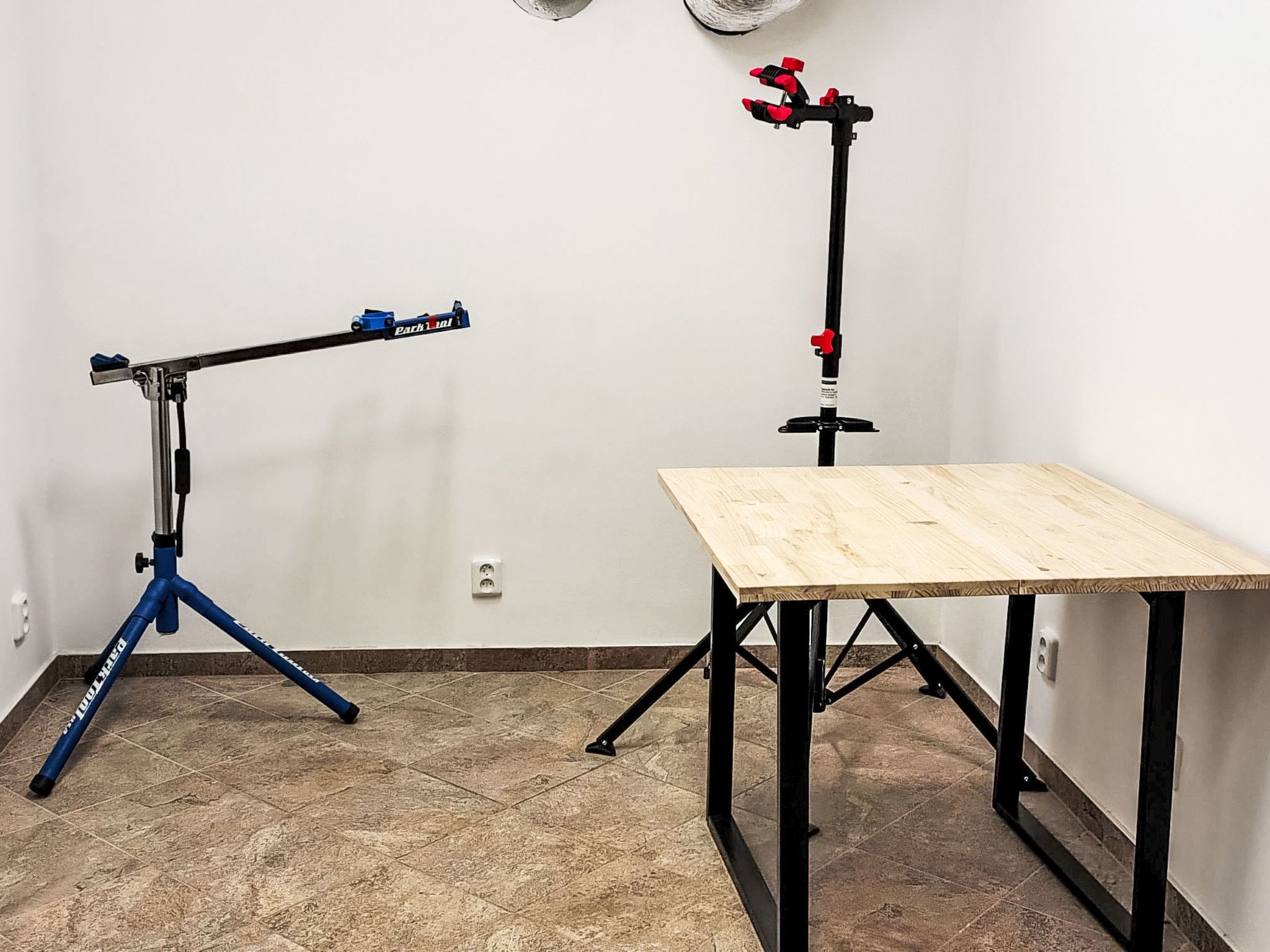 Una habitación con un trípode, una mesa y un dispositivo fijado a la pared.