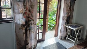 Une pièce donnant sur un jardin, avec une porte-fenêtre, une petite table avec des assiettes et un paillasson.