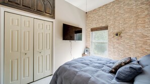 A bedroom with a bed, a wardrobe, a television, and a brick wall. - Peaceful Farm Stay Near Cuyahoga Valley NP (Cuyahoga Falls)