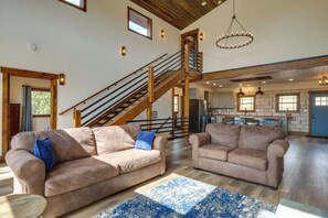 A spacious living area with two sofas, a wooden staircase, and a kitchen in the background. - On 7 Acres! Scenic Home w/ Game Room in Fairplay (Fairplay)