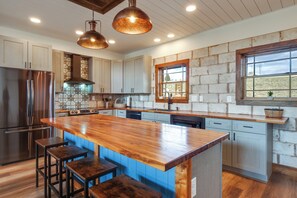 A kitchen with a wooden island, bar stools, stainless steel appliances, and a stone backsplash. - On 7 Acres! Scenic Home w/ Game Room in Fairplay (Fairplay)