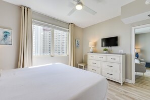 Une chambre d’hôtel avec un lit, une commode, une télévision et une fenêtre avec des rideaux.