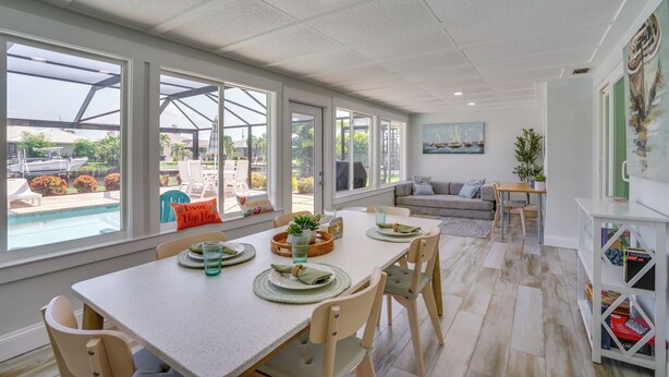 Amplia habitación con una gran mesa de comedor, sillas y vista a una piscina.