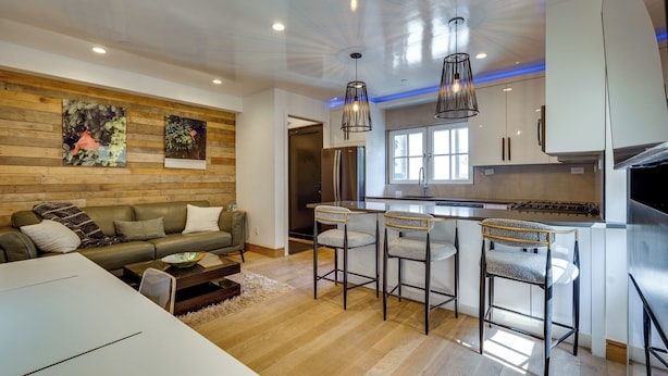 Una cocina moderna con taburetes de bar, una mesa de comedor y un sofá en la sala de estar.