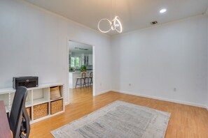 A spacious living area with a wooden floor, a white wall, a kitchen in the background, and a ceiling light fixture. - Serene & Sleek Family Retreat w/ Office in Shirley (Shirley)