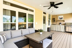A covered patio with a sofa, a table, and a ceiling fan. - 1 Block to Beach: Fire Pit, Outdoor Kitchen, Bikes (Galveston)