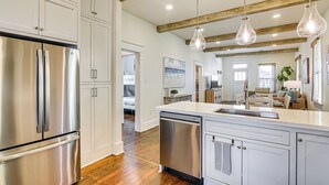 A modern kitchen with stainless steel appliances, wooden beams, and pendant lighting. - 1 Block to Beach: Fire Pit, Outdoor Kitchen, Bikes (Galveston)