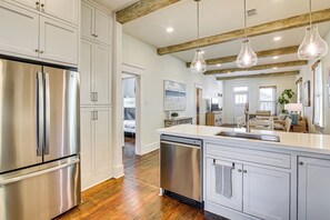 A modern kitchen with stainless steel appliances, wooden beams, and pendant lighting. - 1 Block to Beach: Fire Pit, Outdoor Kitchen, Bikes (Galveston)