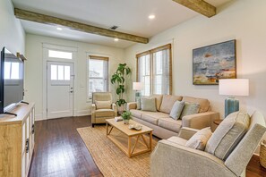 A living room with a sofa, armchairs, a coffee table, a TV, and a painting on the wall. - 1 Block to Beach: Fire Pit, Outdoor Kitchen, Bikes (Galveston)