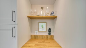 Una cucina con un piano di lavoro in legno, una mensola con bicchieri, un quadro incorniciato e una piccola statua.