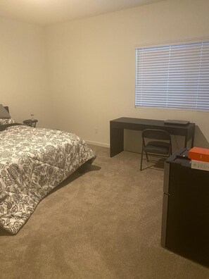 A bedroom with a bed, a desk, a chair, and a window with blinds. - Serene 4-bedroom building with AC in charming Patterson (Patterson)