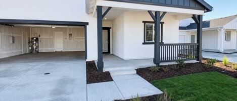 A modern two-story house with a covered porch, a garage, and a well-maintained lawn.