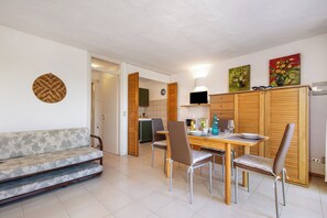 Una sala de estar con sofá, mesa de comedor, sillas y una cocina al fondo.