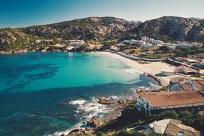An aerial view of a coastal town with clear turquoise waters, rocky cliffs, and buildings with terracotta roofs. - Da Marta 10 Passi Dal Mare (Arzachena)