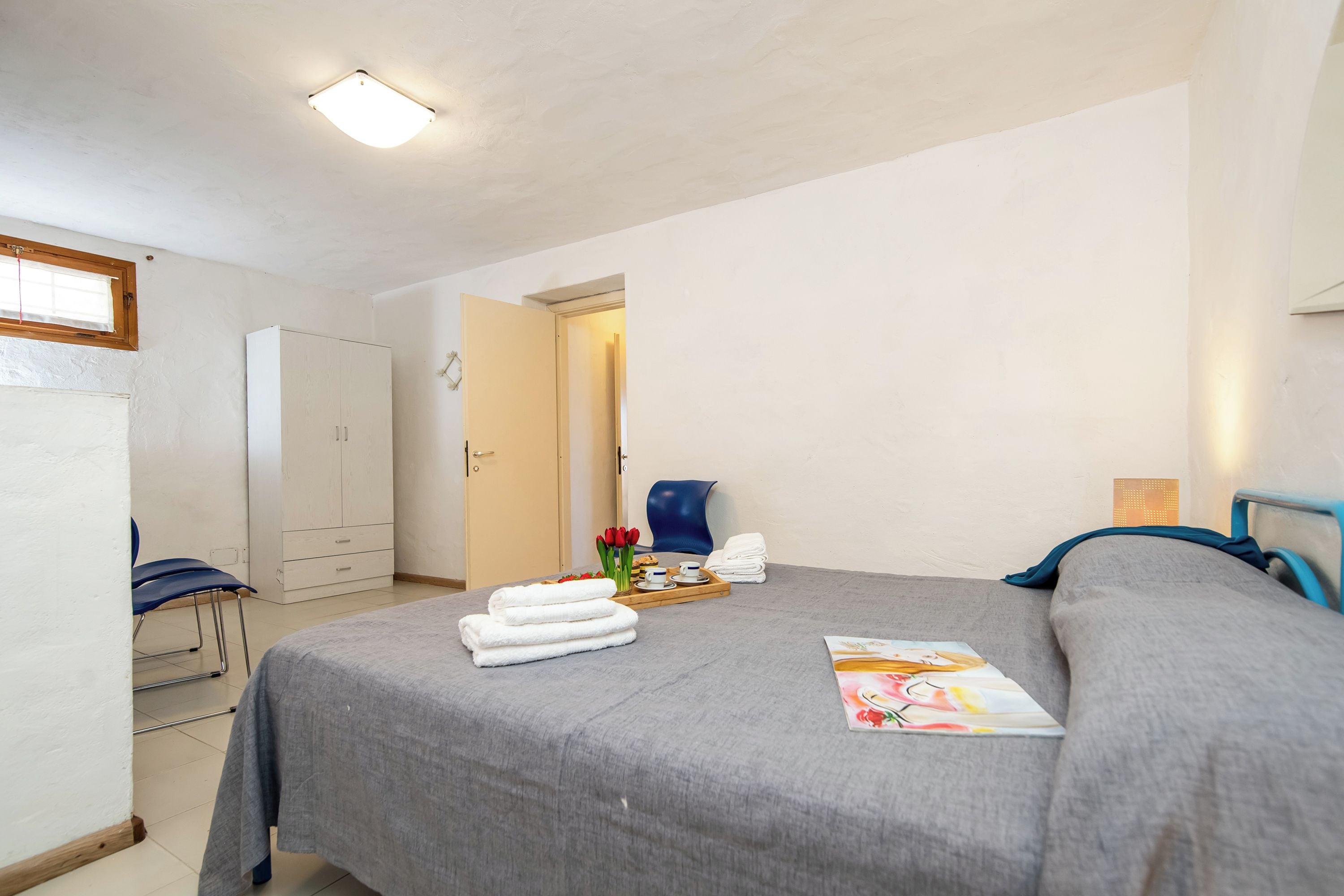 Une chambre à coucher comprenant un lit, une chaise, une armoire et une porte donnant sur une autre pièce.