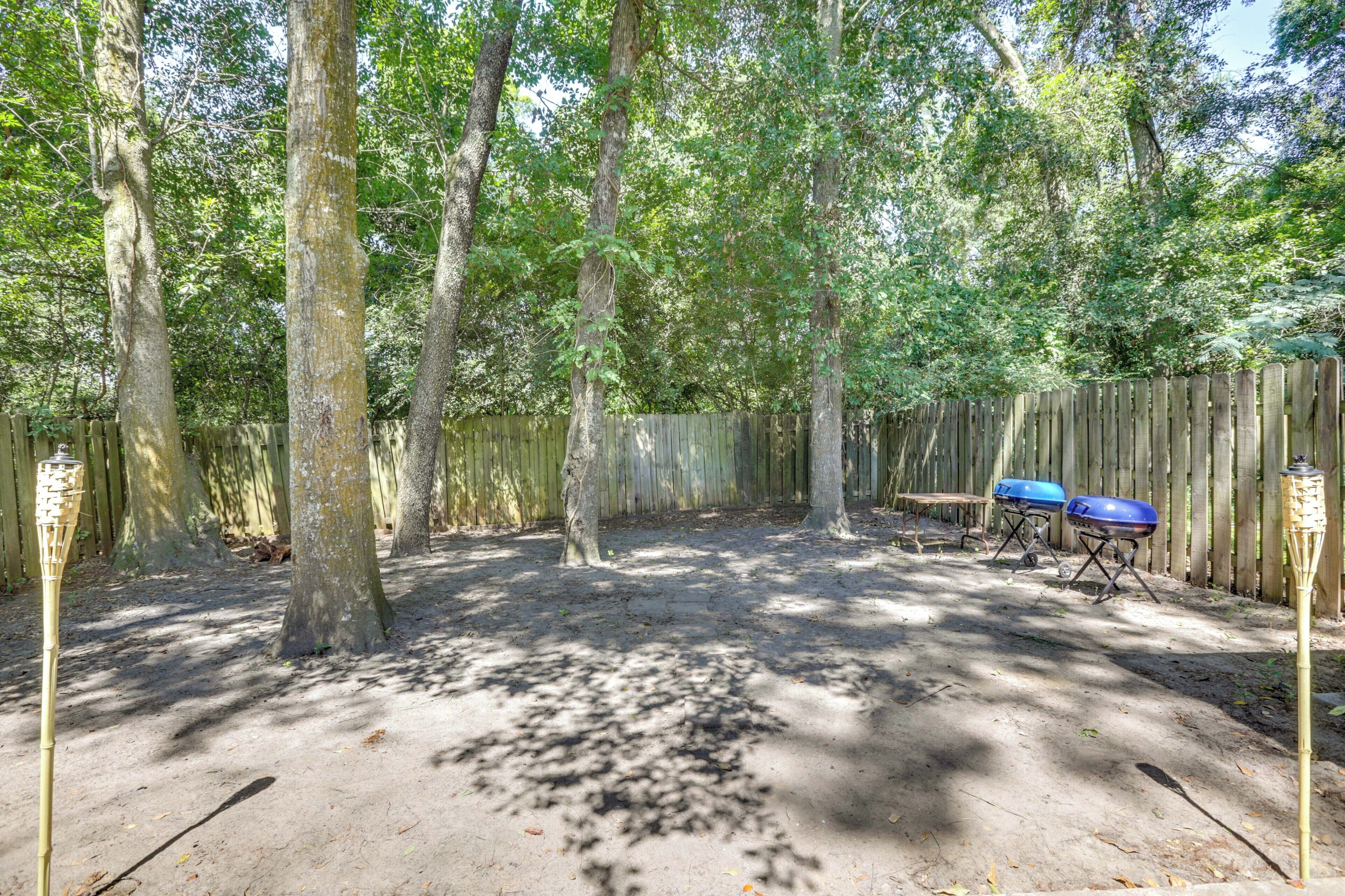 Un jardin avec des arbres, une clôture en bois et des barbecues.