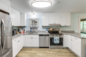 A modern kitchen with white cabinets, stainless steel appliances, and a granite countertop. - 11 Mi to Ocean City Beach! Family-Friendly Haven (Ocean Pines)