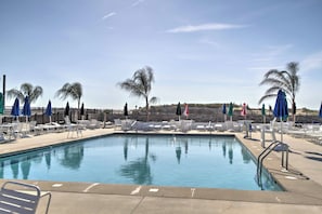 A swimming pool with lounge chairs and umbrellas, surrounded by a stone wall and palm trees. - 11 Mi to Ocean City Beach! Family-Friendly Haven (Ocean Pines)