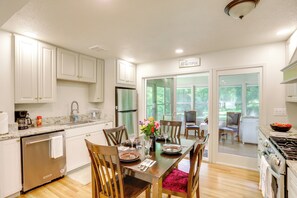 A kitchen with white cabinets, a dining table set for four, and a view through glass doors to an outdoor area. - Explore Oberlin! Home 1 Mi to Main Street & Campus (Oberlin)