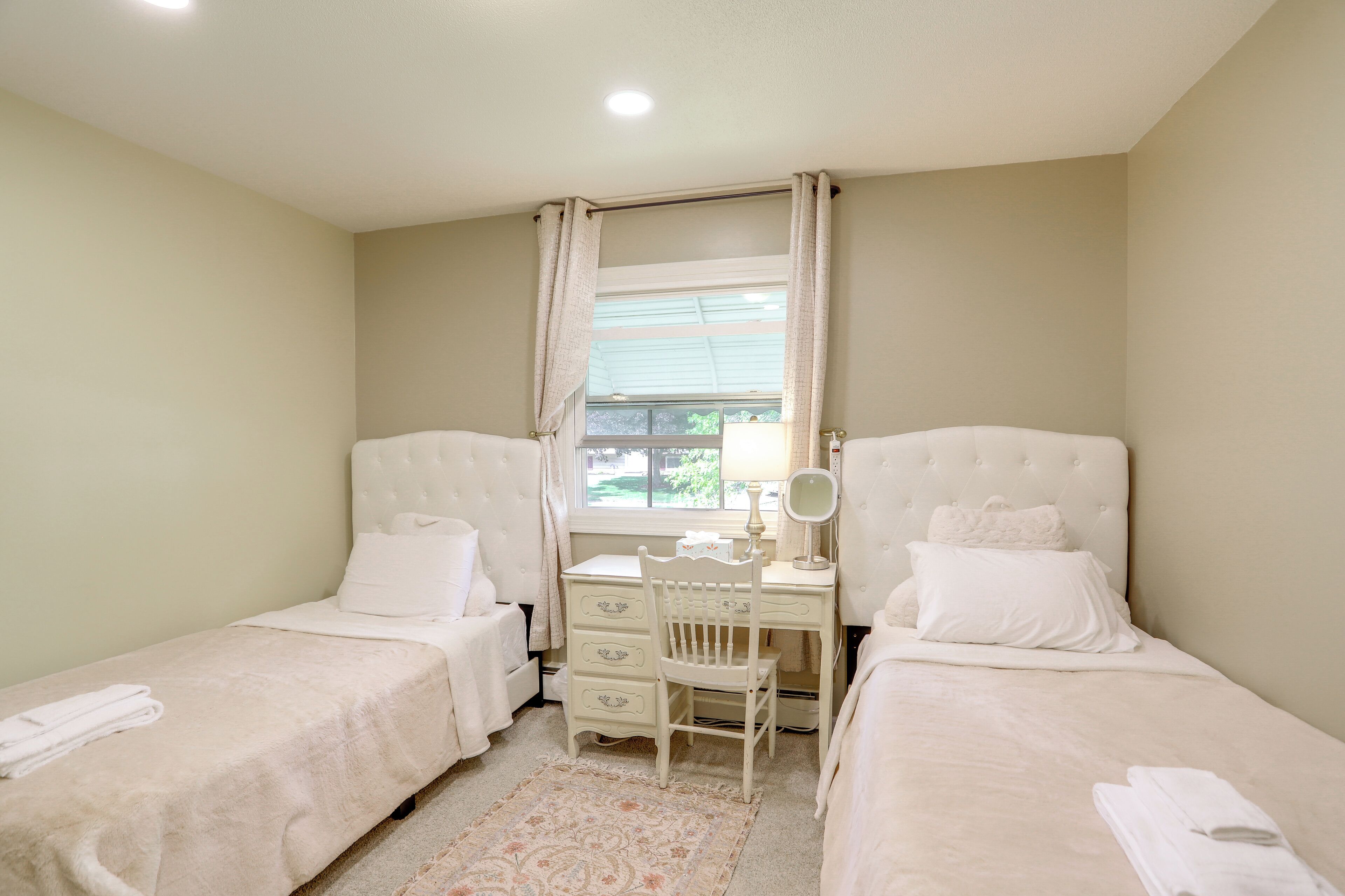 A bedroom with two beds, a desk, and a chair.
