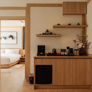 Una habitación de hotel moderna con un escritorio de madera, una cama y un refrigerador pequeño.