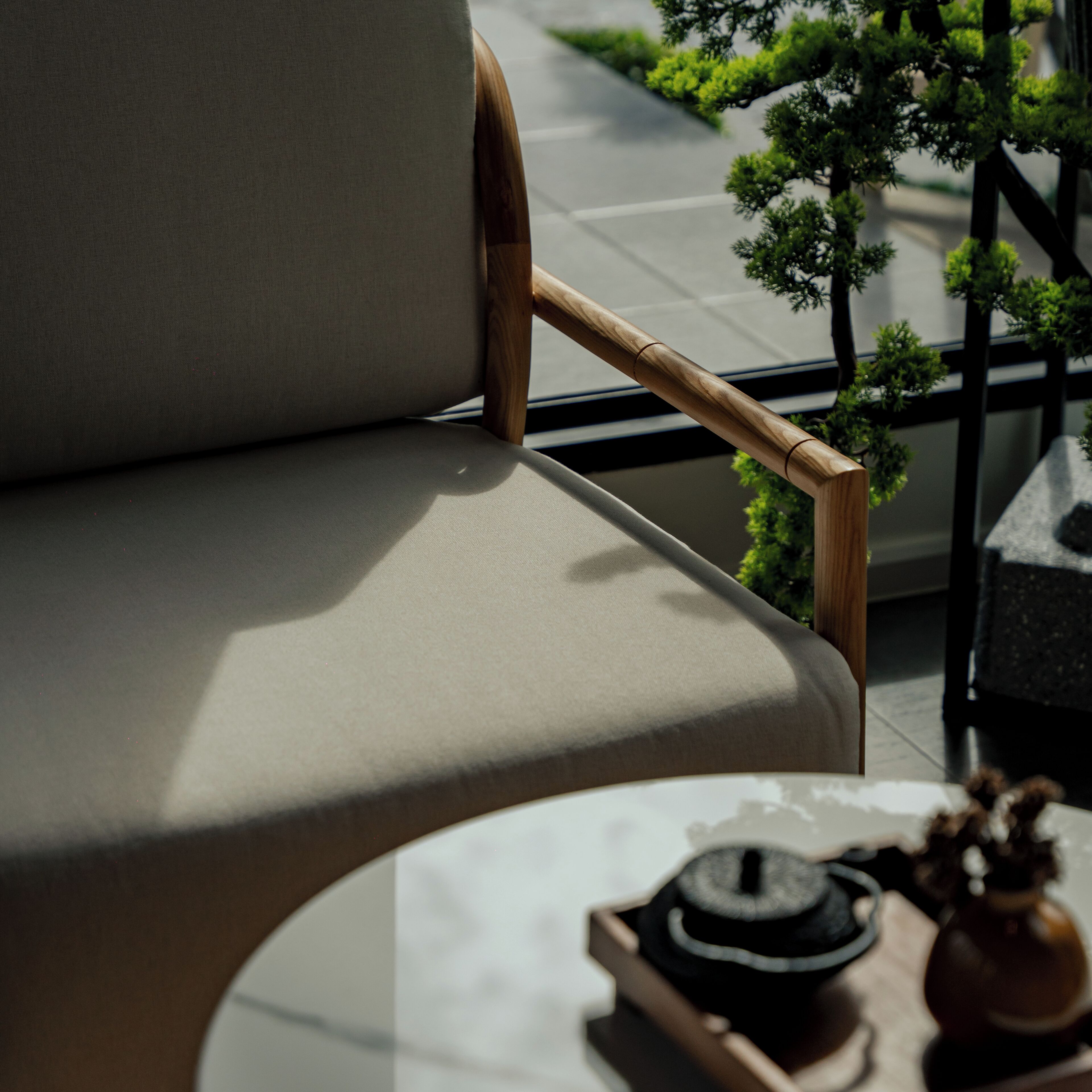 Una silla moderna con un reposabrazos de madera y un asiento acolchado, ubicada junto a una mesa con un adorno pequeño.