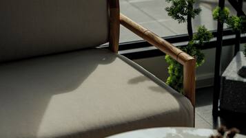 Una silla moderna con un reposabrazos de madera y un asiento acolchado, ubicada junto a una mesa con un adorno pequeño.