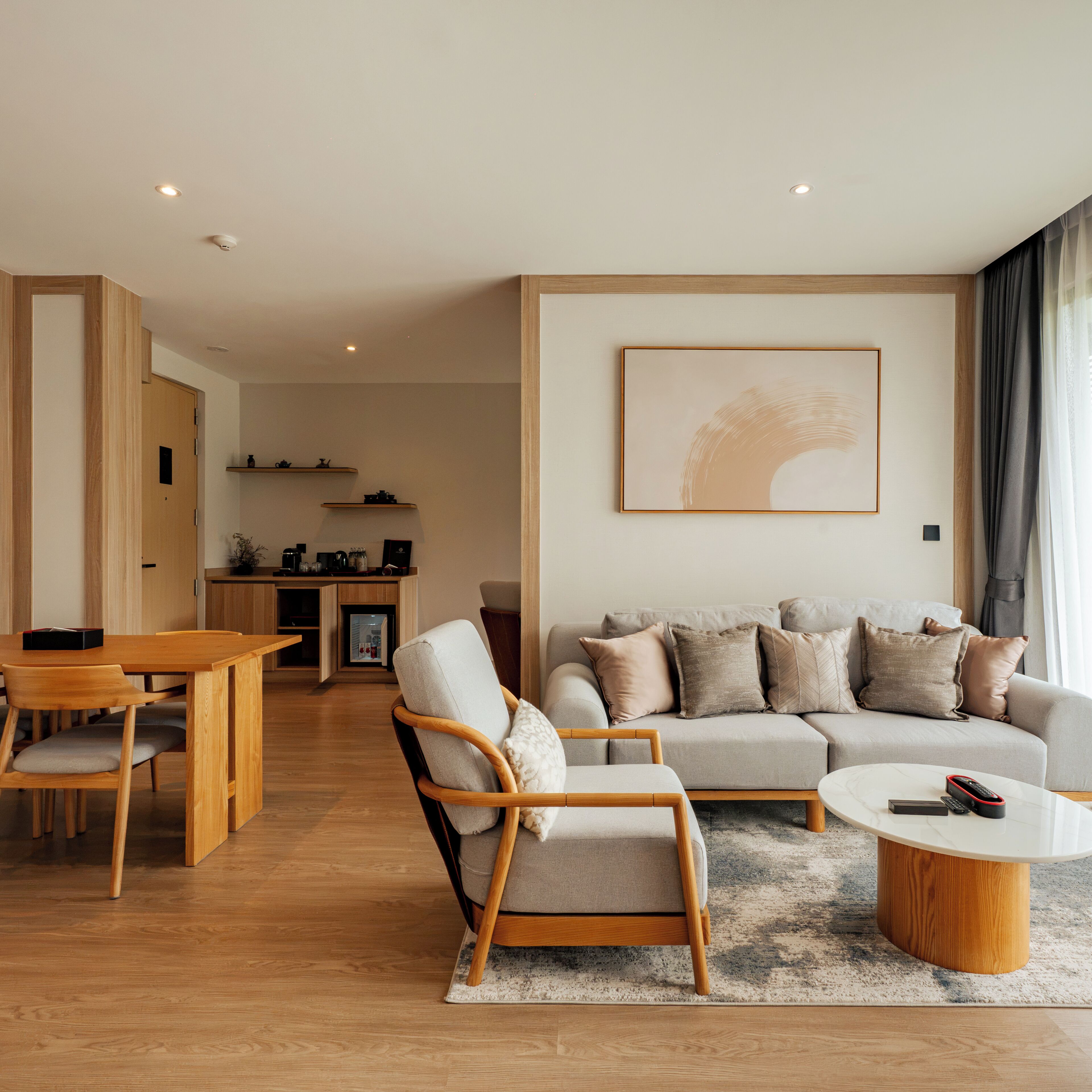A modern living room with a sofa, armchairs, a coffee table, and a dining area with a wooden table and chairs.