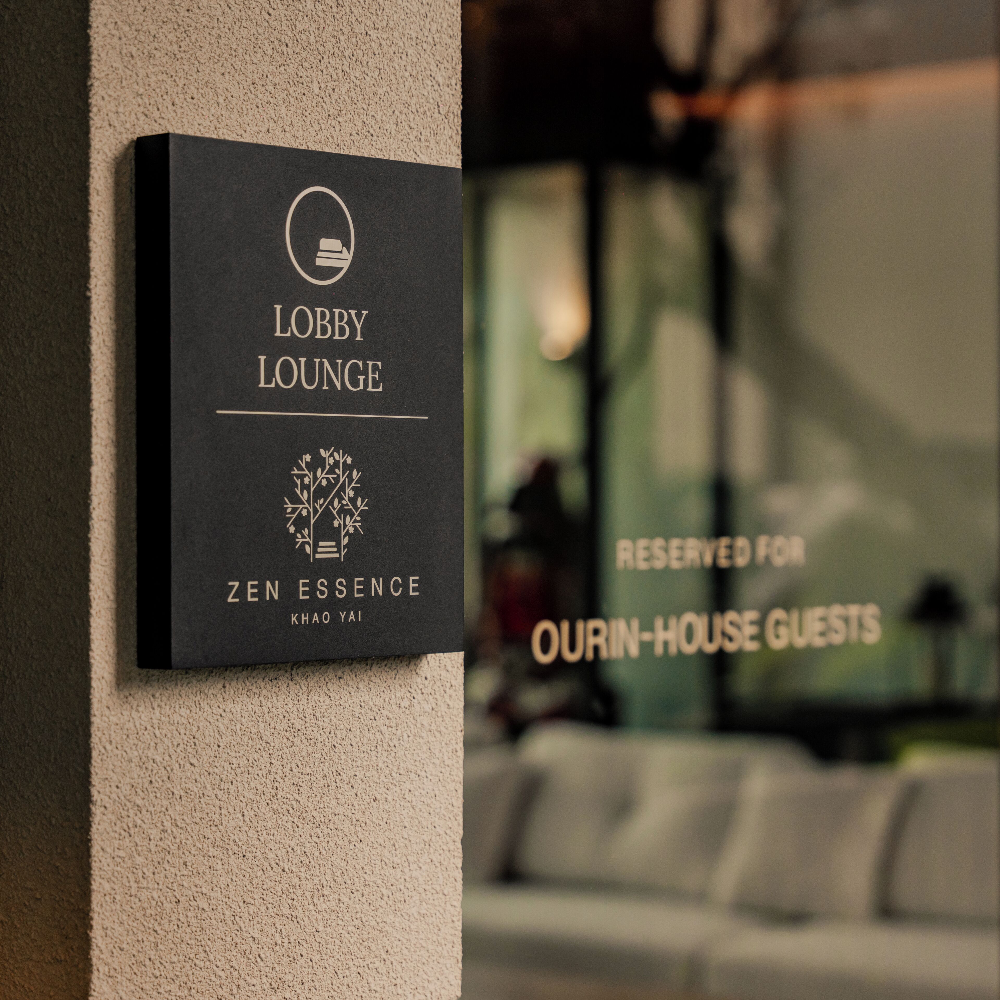 Ein Schild für die Lobby-Lounge mit einem Logo und dem Namen 'ZEN ESSENCE' an einer Wand.
