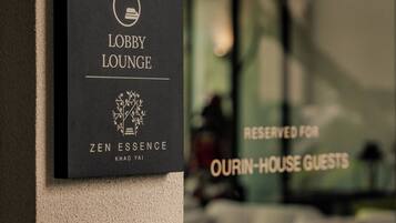 Ein Schild für die Lobby-Lounge mit einem Logo und dem Namen 'ZEN ESSENCE' an einer Wand.