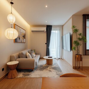 A modern living room with a sofa, coffee table, and a TV mounted on the wall. - Zen Essence Khao Yai (Pak Chong)